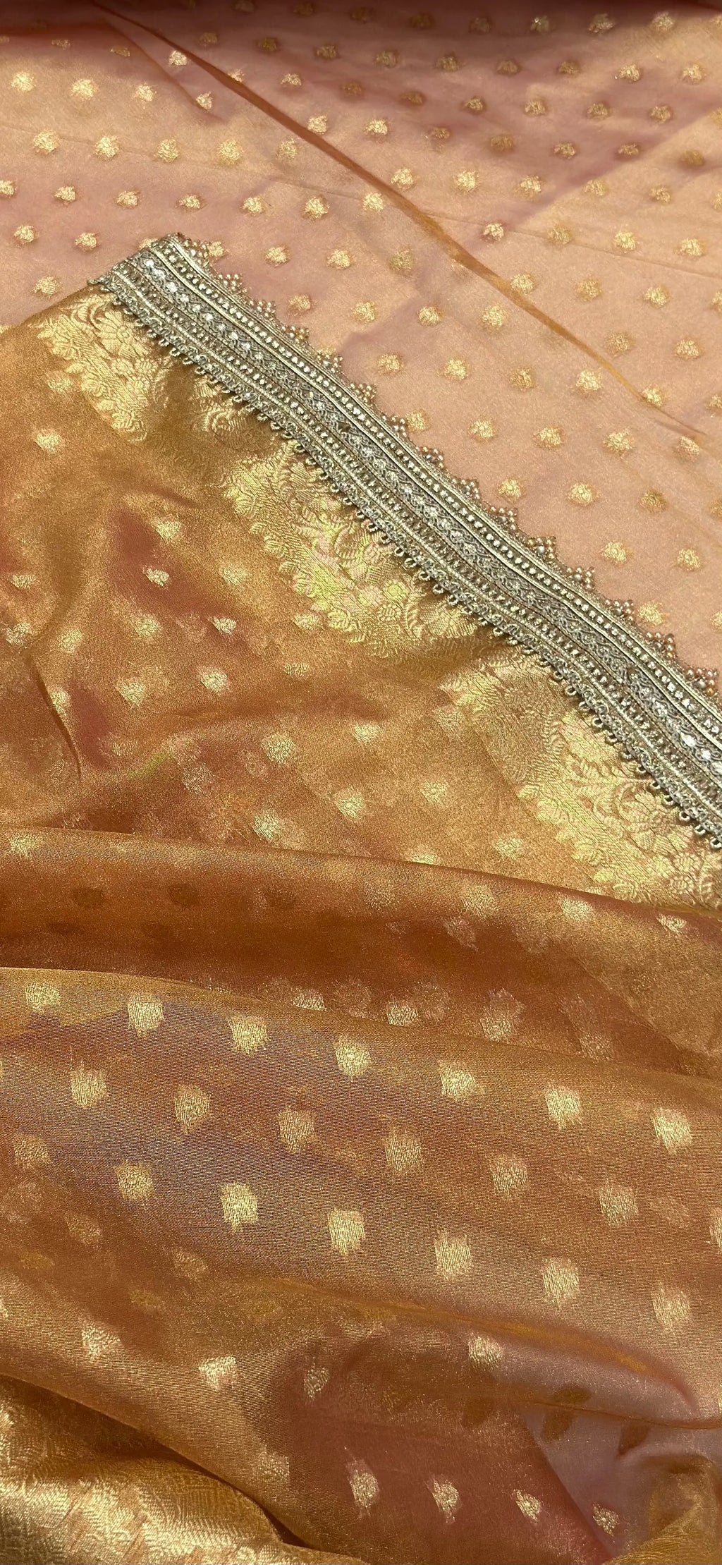 Close-up of a gold fabric with intricate patterns and embroidery.