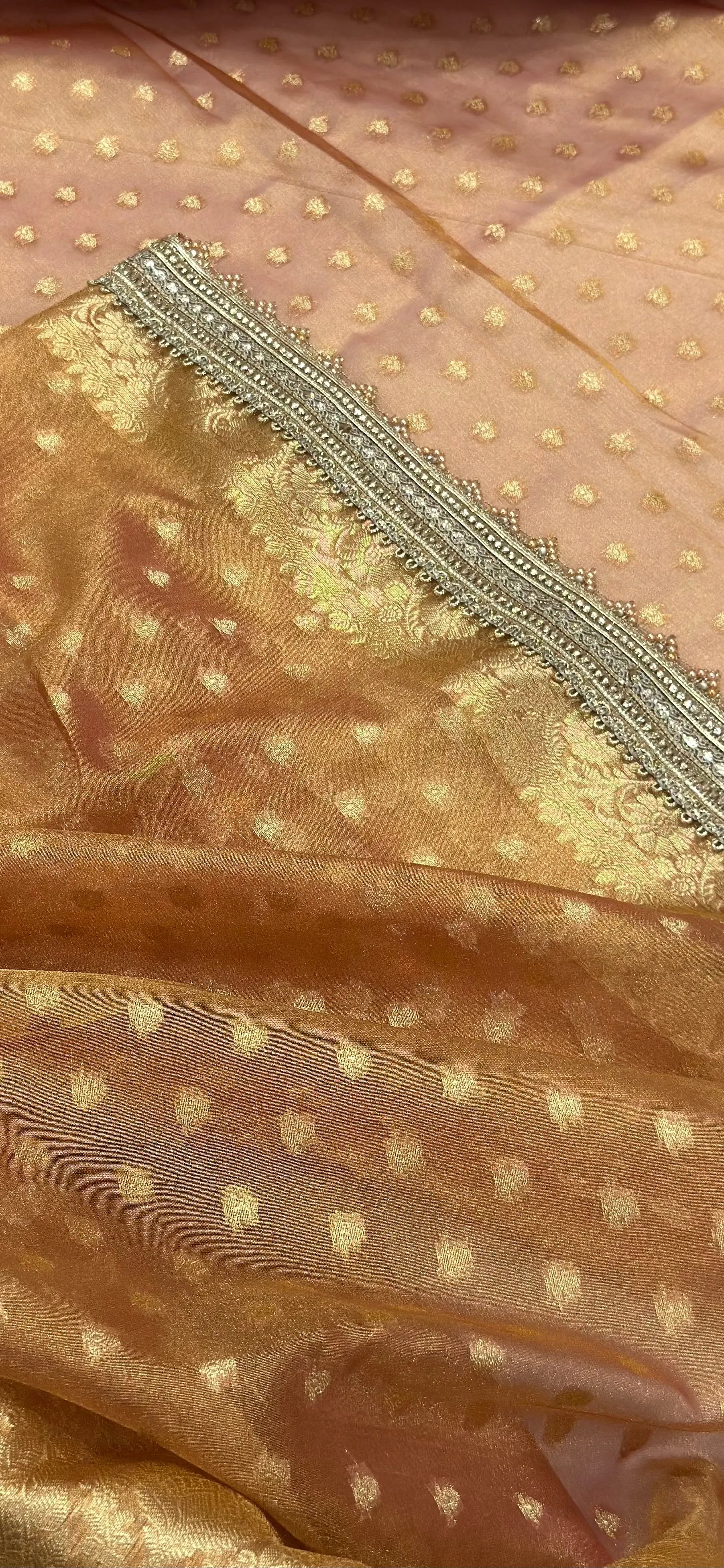 Close-up of a gold fabric with intricate patterns and embroidery.